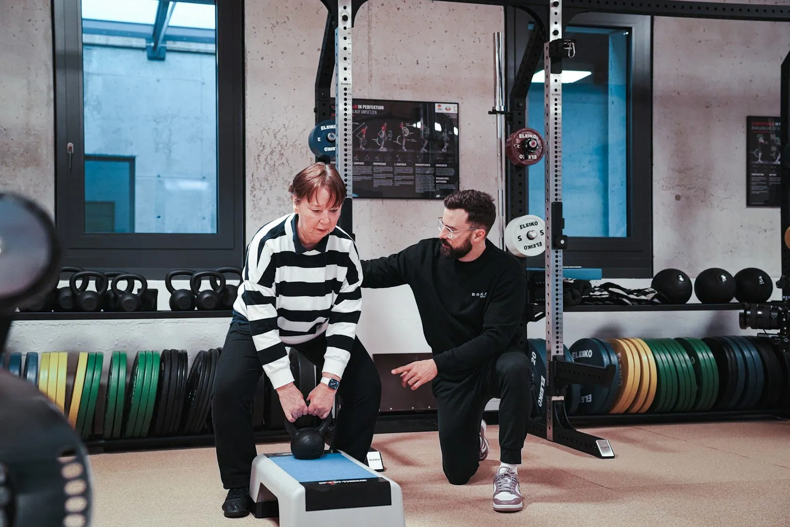 Seniorentraining im BRIKS Studio Heidelberg: Trainer leitet eine Seniorin bei einer Kettlebell-Übung an